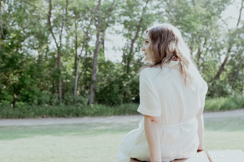 Candid portrait of a woman sitting on a park bench, taken during an Edmonton photo session.