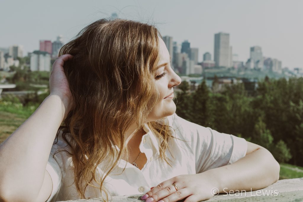 Candid portrait of a woman with the downtown Edmonton skyline in the background.