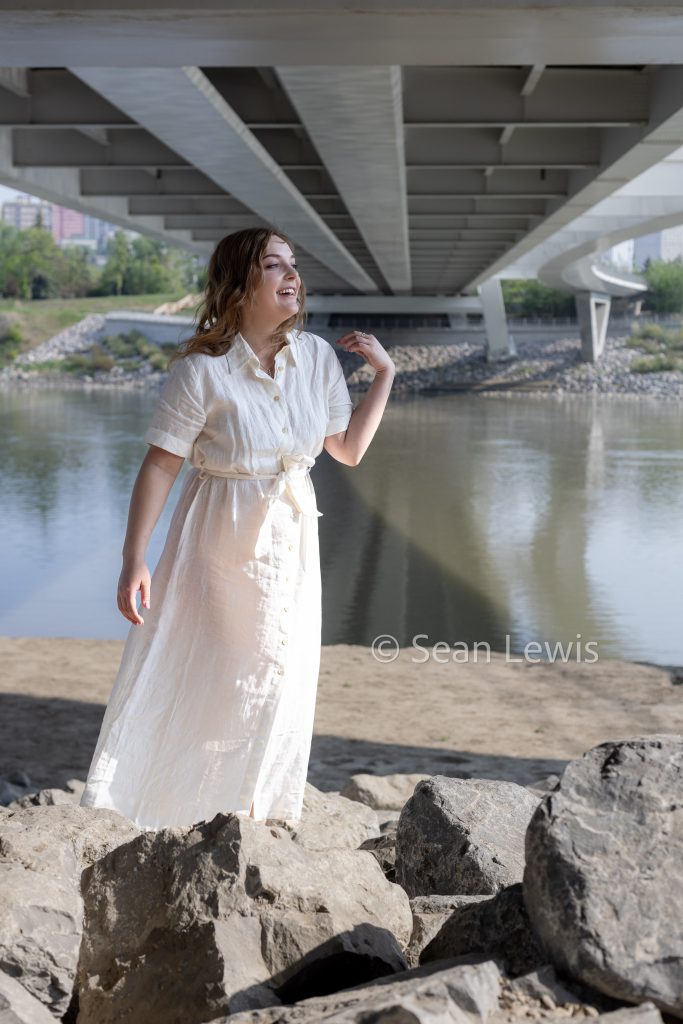 Personal branding photo of a woman in a white dress on the bank of Edmonton's river valley.