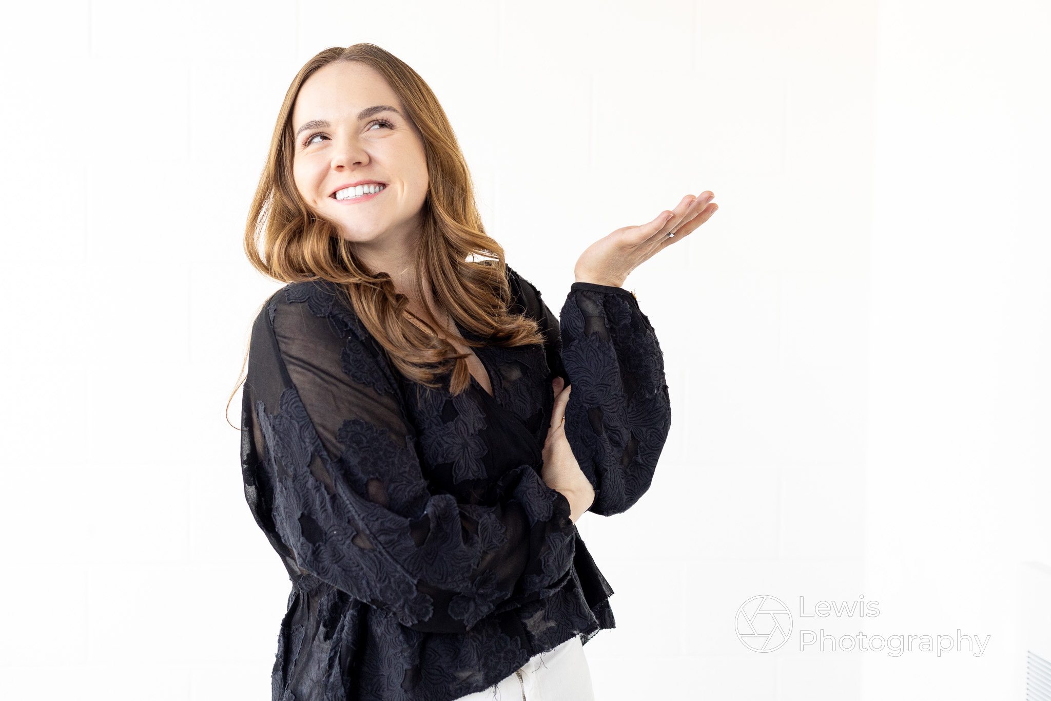 Professional personal branding photo of a woman in a black shirt gesturing, taken with our mobile studio in Edmonton.