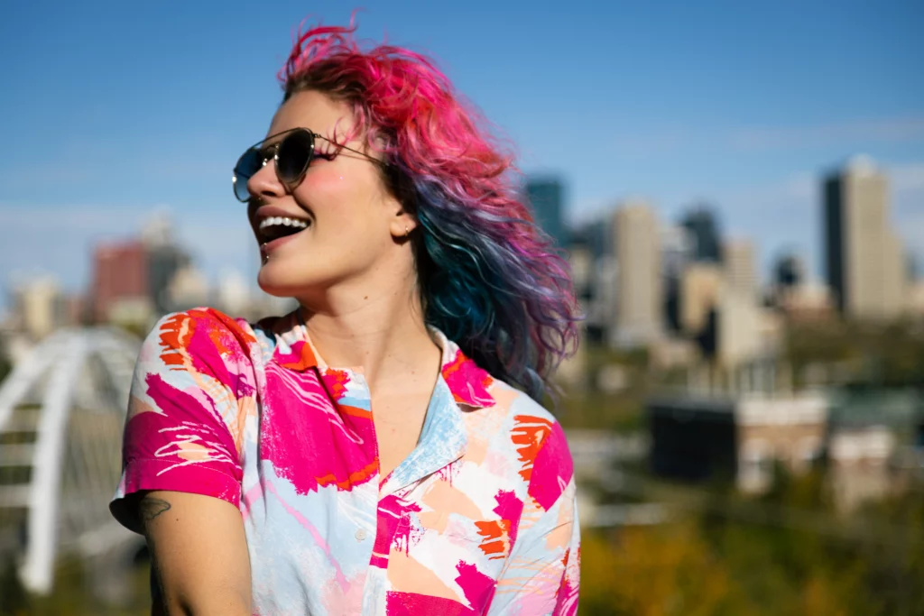 Candid personal branding portrait of a woman with colorful hair laughing in downtown Edmonton.