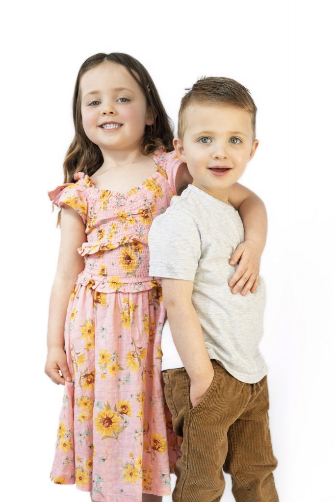 siblings loving the camera at an indoor family photo session